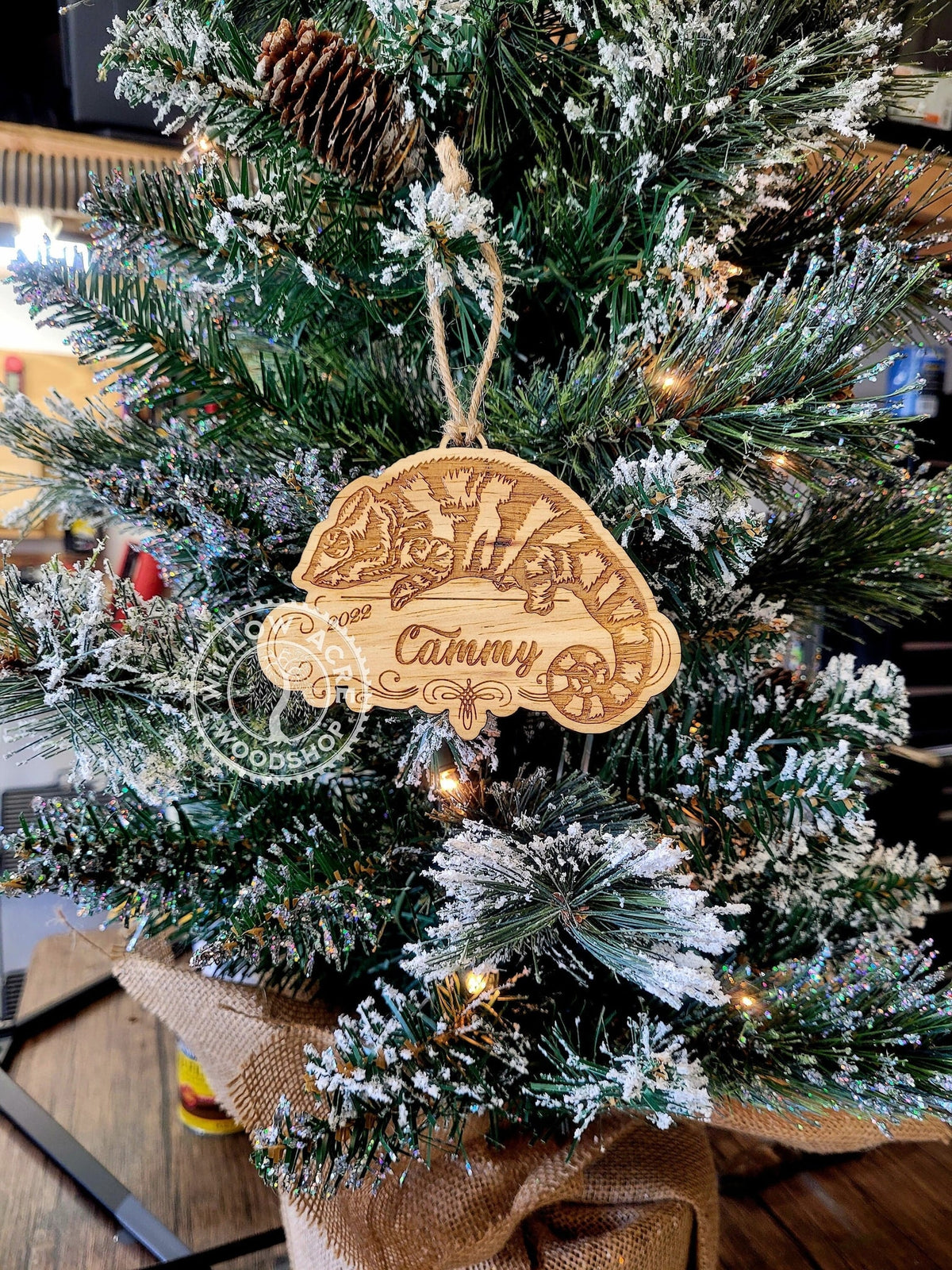 An unpainted chameleon ornament engraved Cammy, hanging on a Christmas tree.