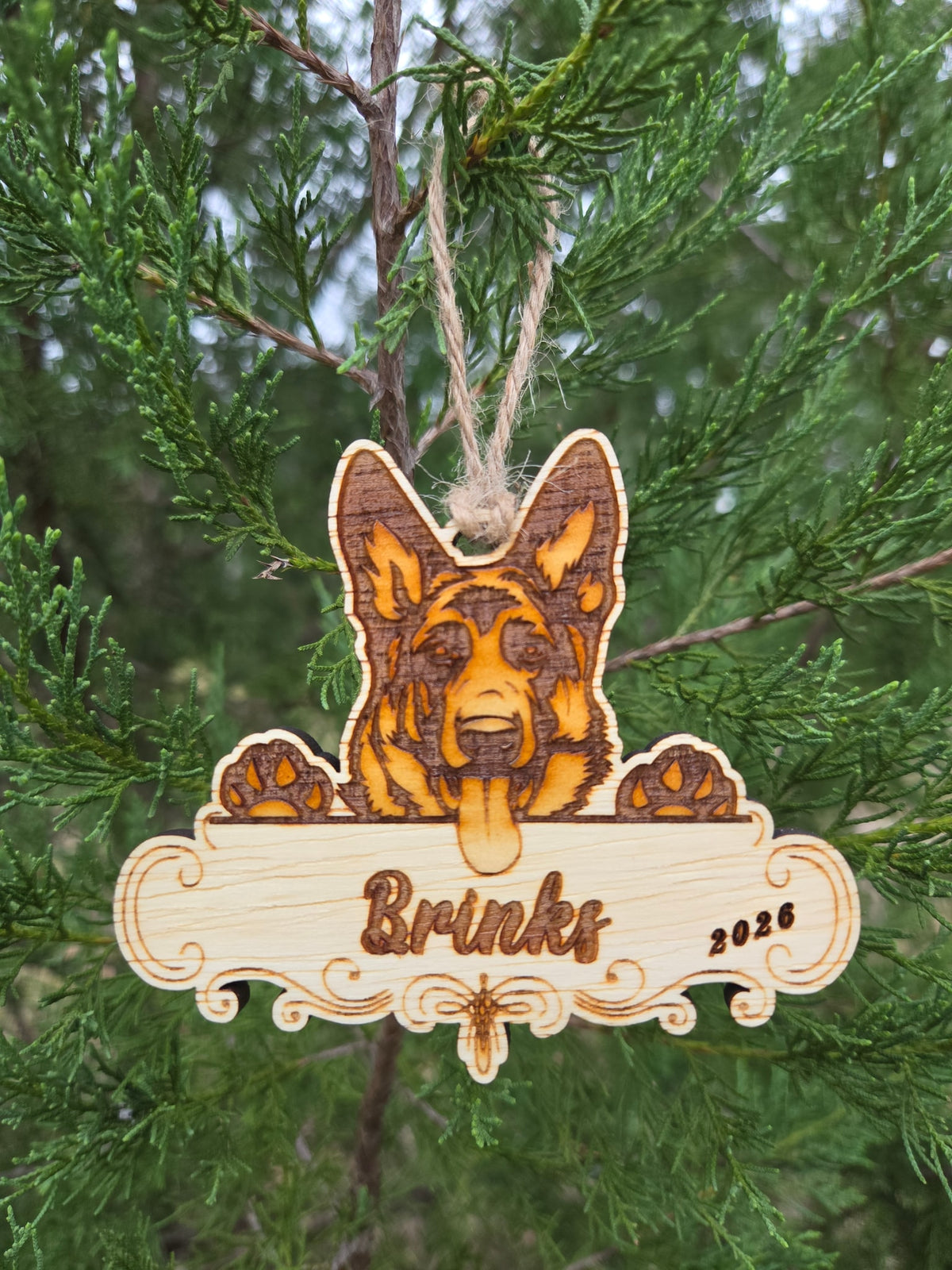 German Shepherd plaque ornament hanging by its twine loop on an evergreen branch