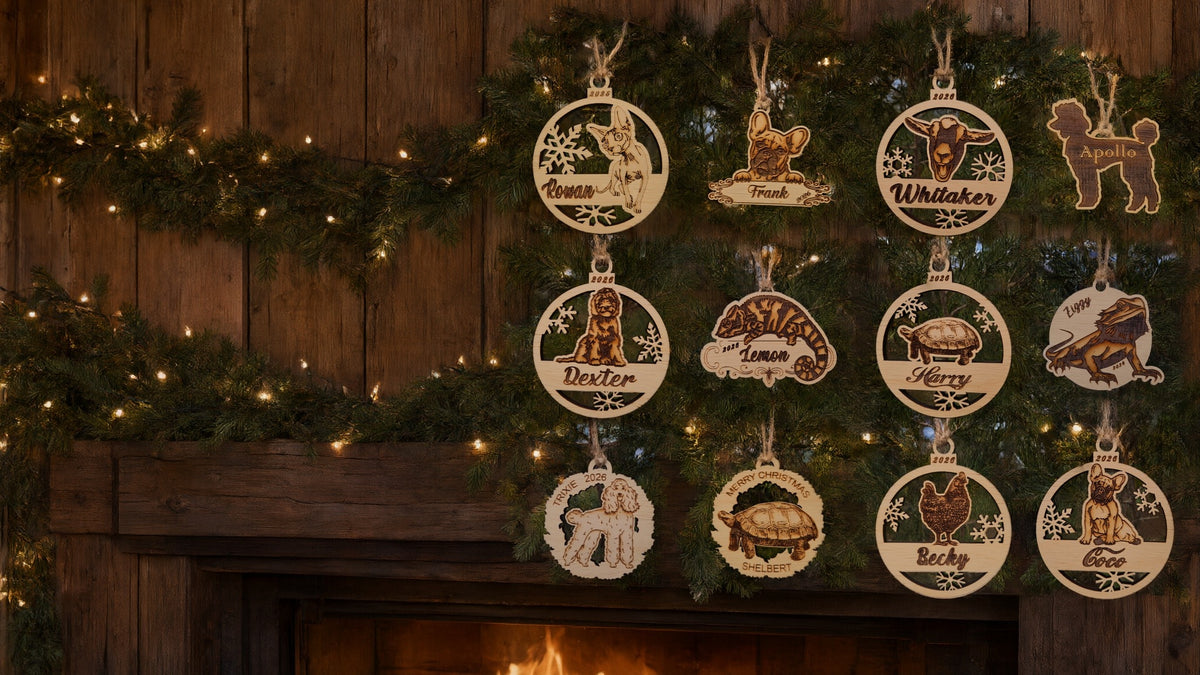 Twelve of our wooden pet ornaments, dogs, cats, a goat, a hen, tortoises and reptiles, hanging on pine garland over a mantel