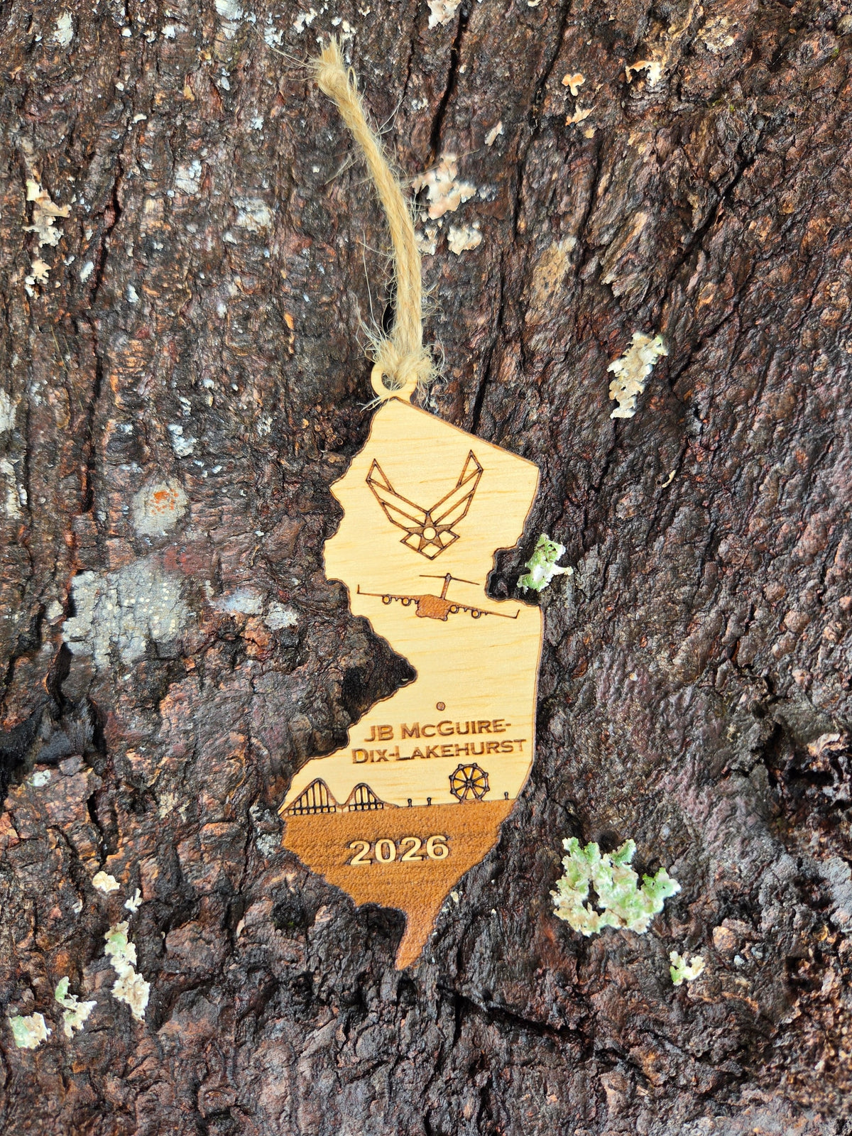 New Jersey-shaped wooden ornament with a C-17A in flight, JB McGuire-Dix-Lakehurst, the boardwalk and the year, on tree bark