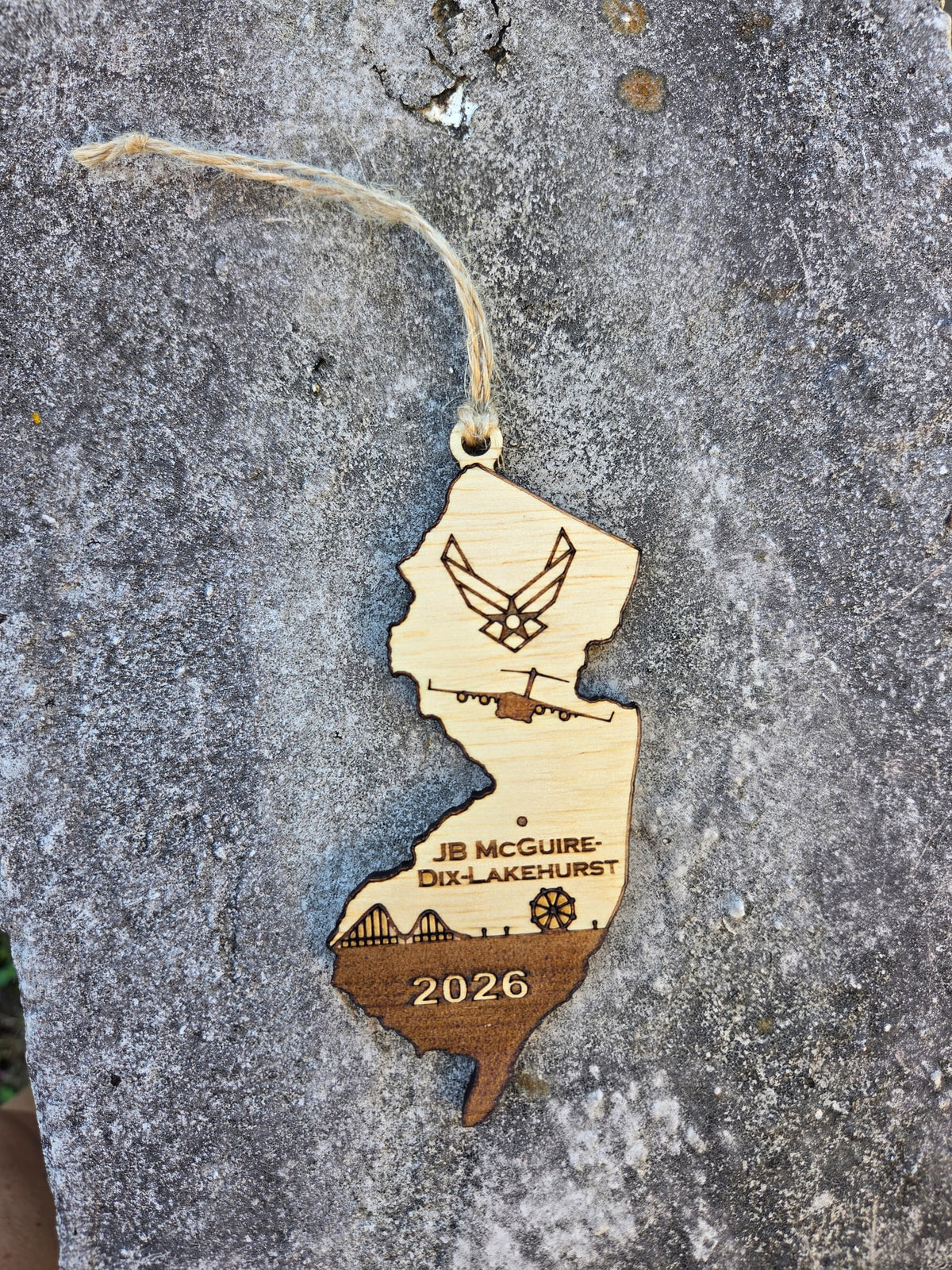 JB McGuire-Dix-Lakehurst New Jersey ornament with its twine loop, lying flat on gray stone
