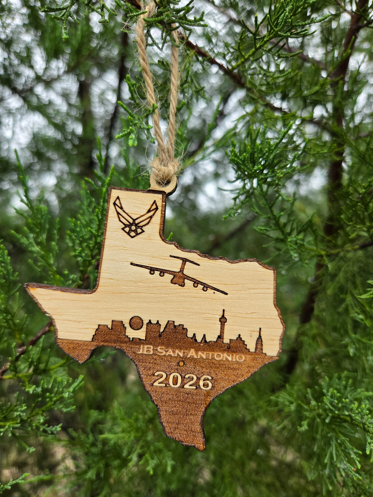 JB San Antonio Texas ornament hanging by its twine loop on an evergreen branch