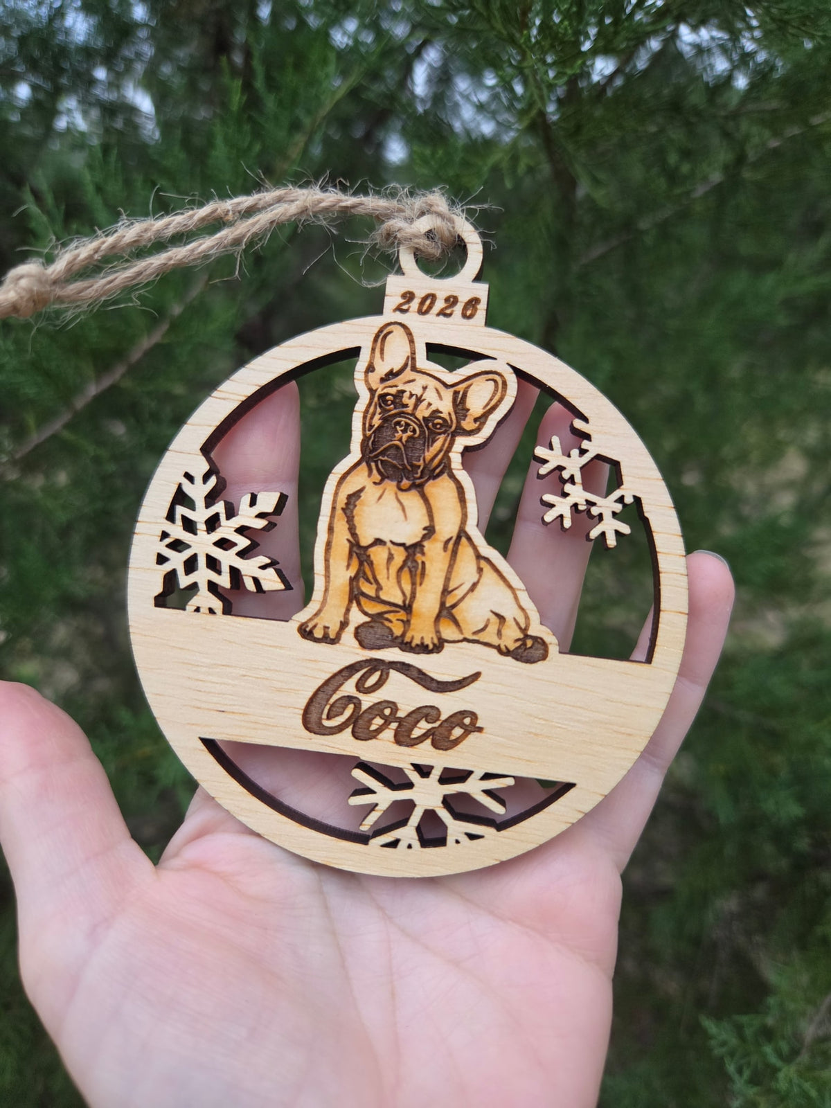 Sitting French Bulldog and snowflakes ornament held in an open hand to show its size