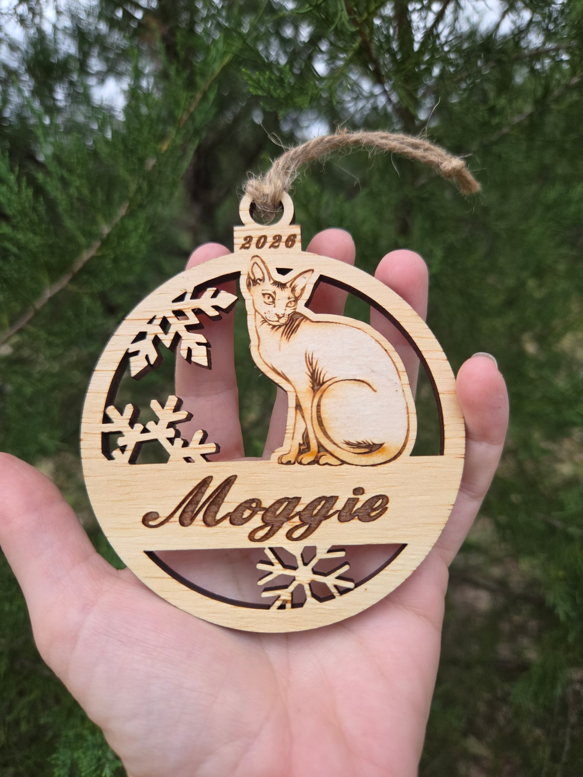 Sitting Sphynx cat ornament held in an open hand to show its size