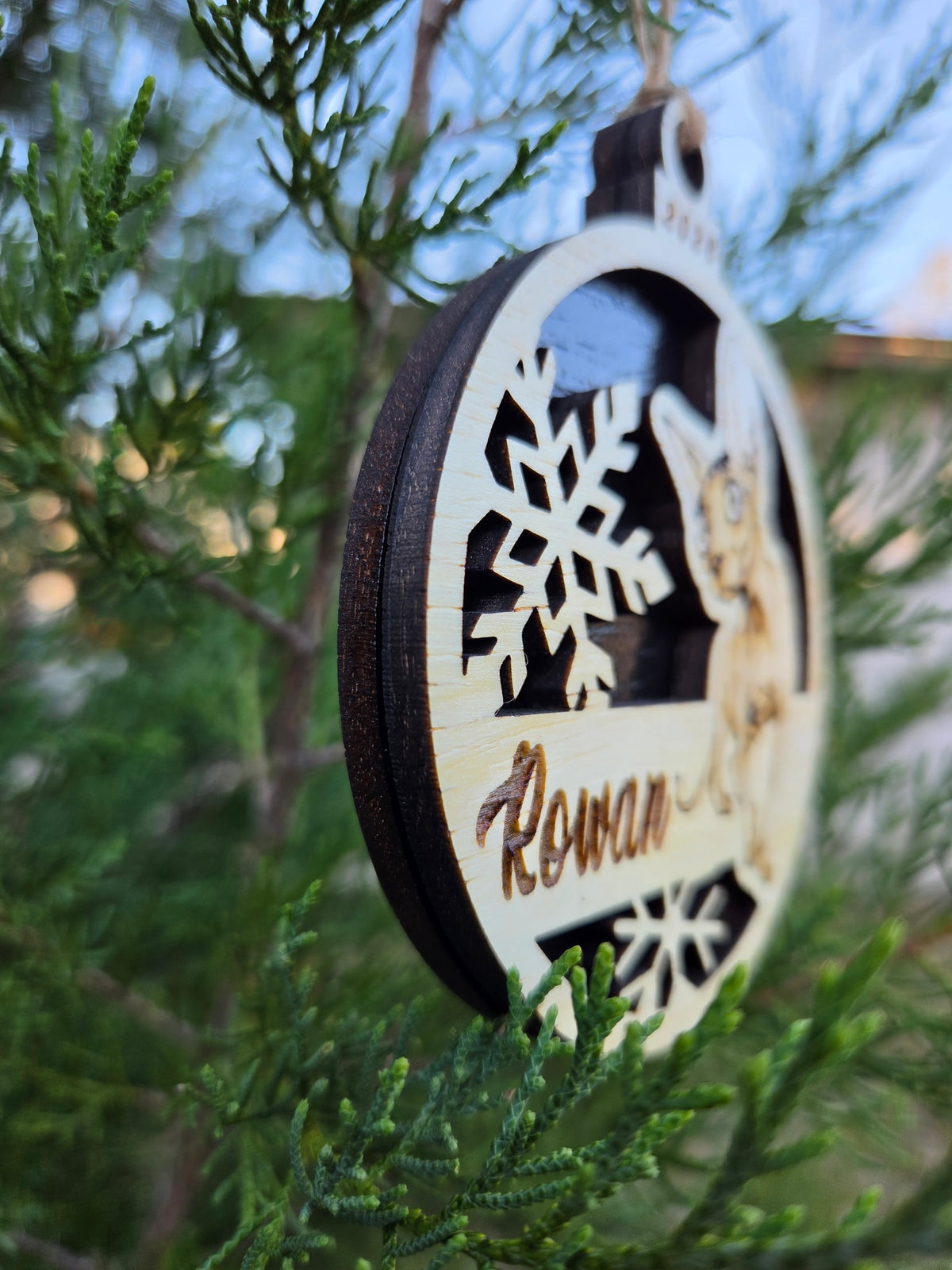 Side view of the Sphynx cat ornament on its black back, showing the two layers of wood