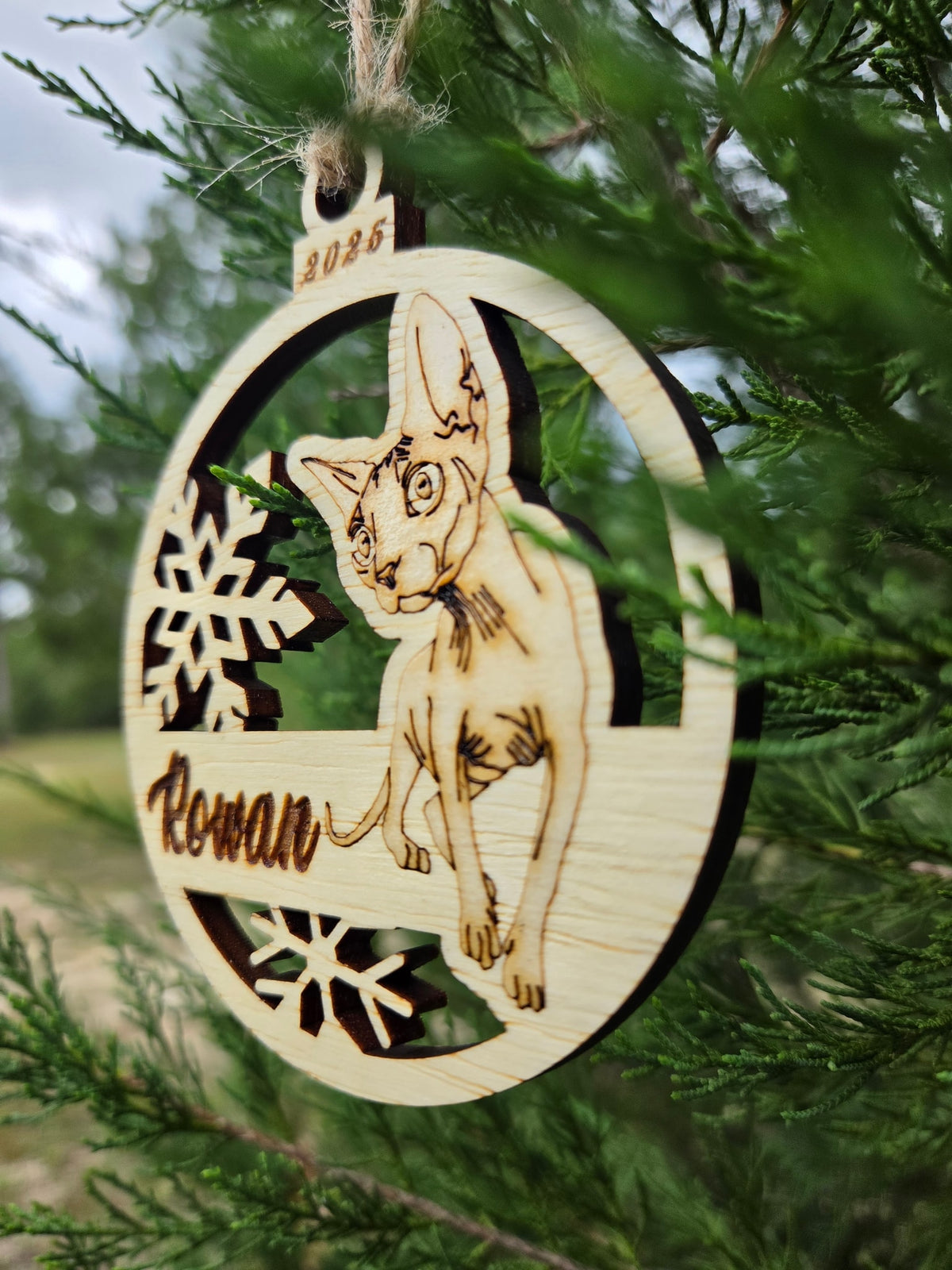 Side view of the Sphynx cat ornament showing the thickness of the wood and the cut-out snowflakes