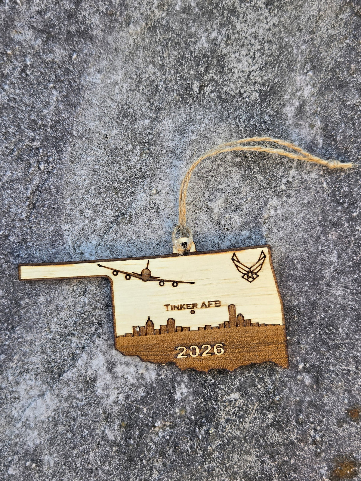 Tinker AFB Oklahoma ornament with its twine loop, lying flat on gray stone