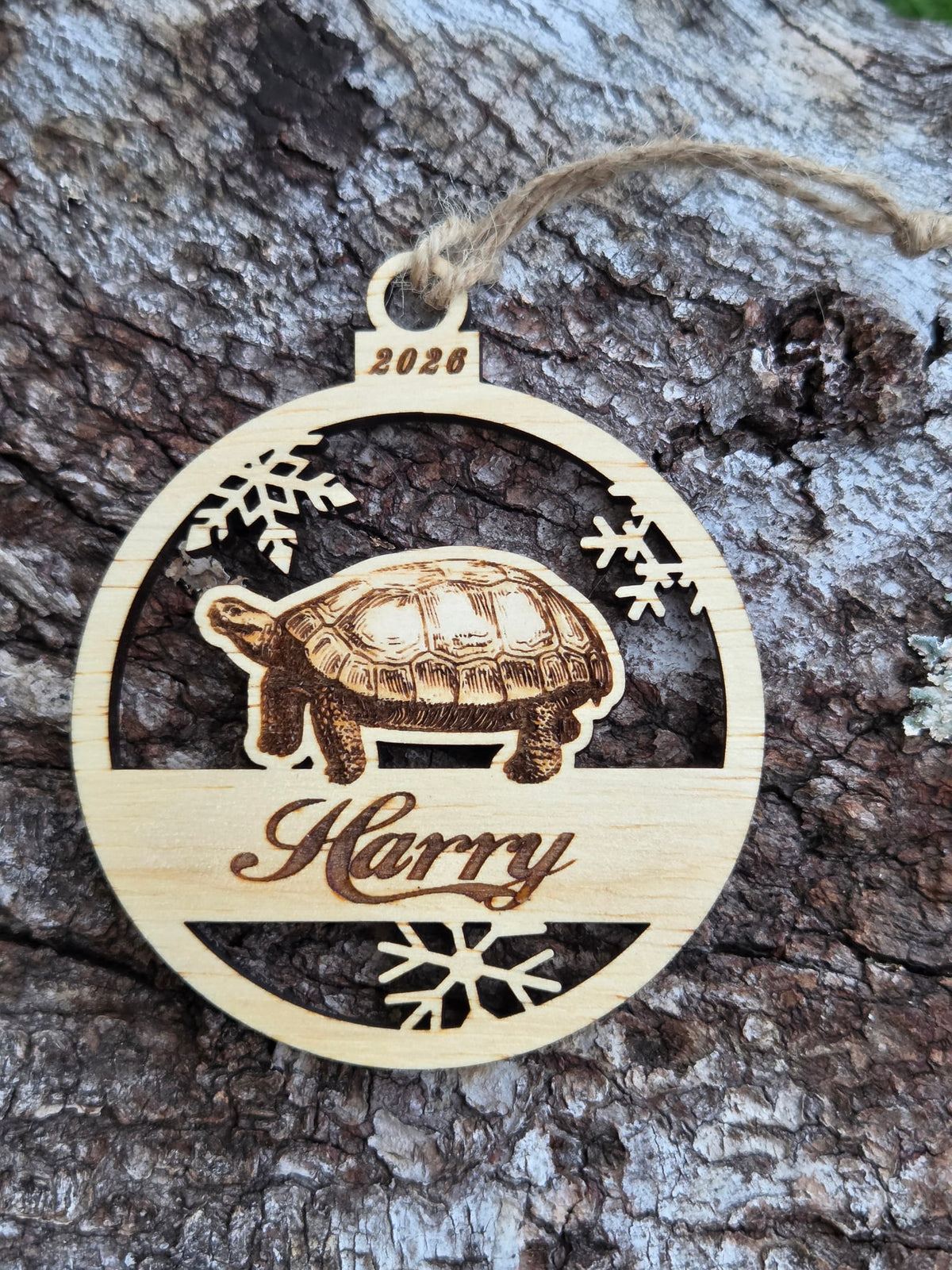 Wooden tortoise and snowflakes ornament, front layer with a sample name and year engraved, shown without its colored back