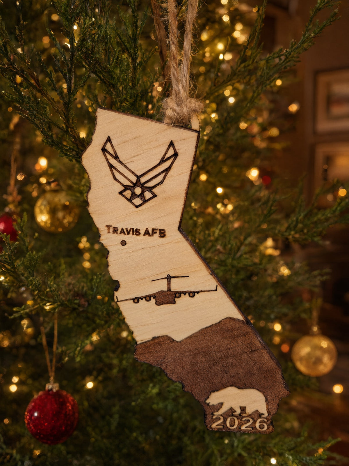 Travis AFB California ornament hanging on a lit Christmas tree with red and gold ornaments