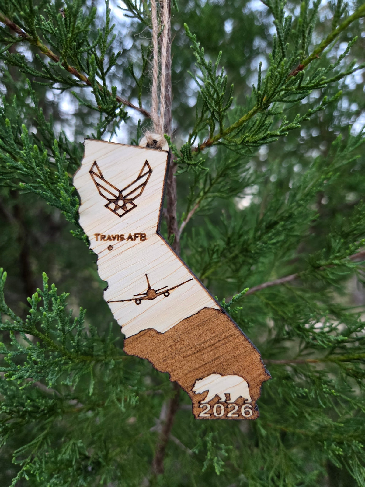 Travis AFB KC-46A California ornament hanging on an evergreen branch